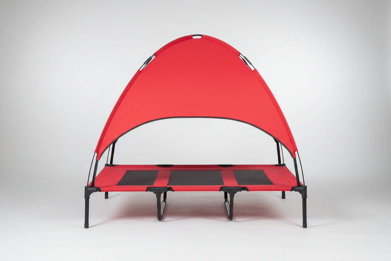 Dog lying on a red pet canopy bed in a home setting with a brick wall and plant in the background.